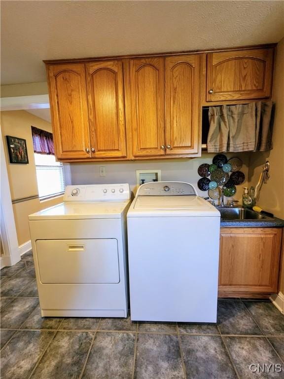 laundry room with a textured ceiling, cabinets, independent washer and dryer, and sink