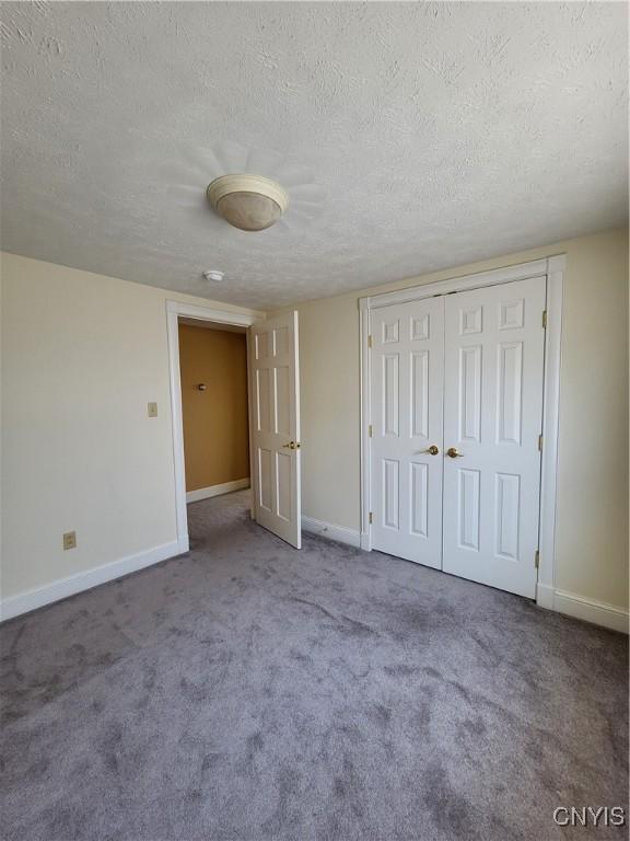 unfurnished bedroom with carpet floors, a textured ceiling, and a closet