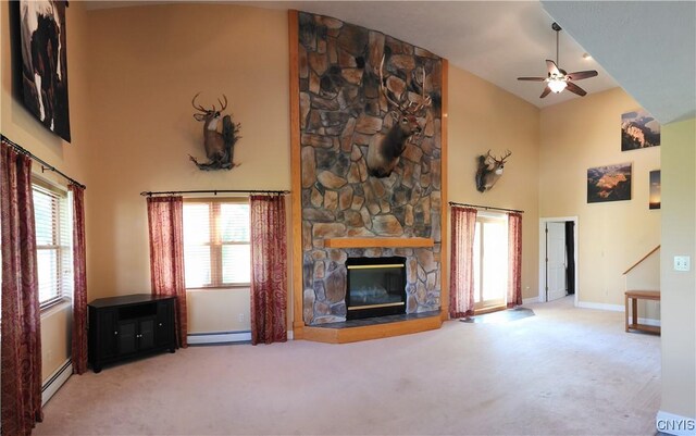 unfurnished living room with ceiling fan, high vaulted ceiling, a baseboard heating unit, a fireplace, and carpet