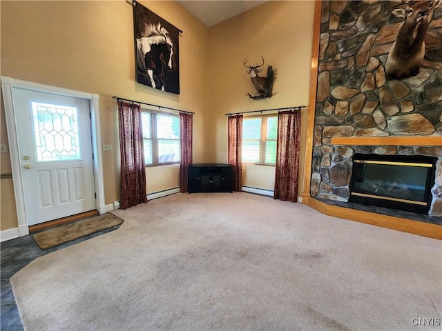 unfurnished living room featuring a stone fireplace, plenty of natural light, and a baseboard heating unit