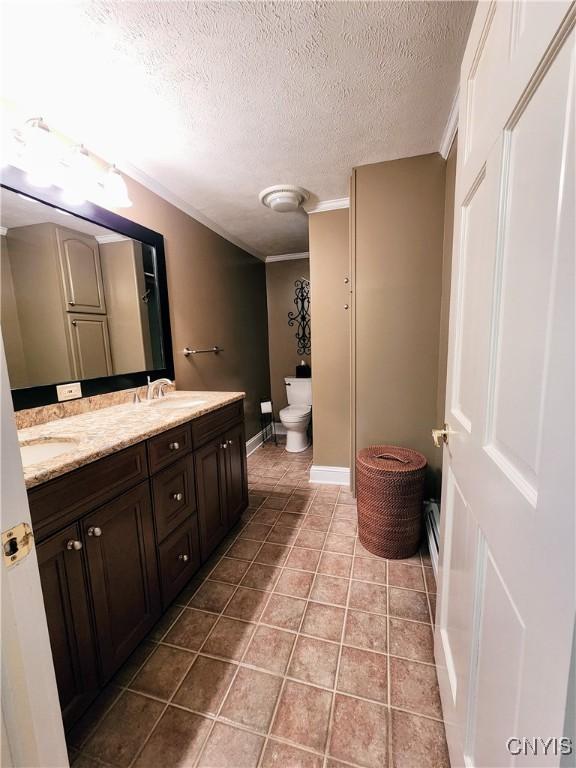 bathroom featuring vanity, tile patterned floors, crown molding, toilet, and a textured ceiling