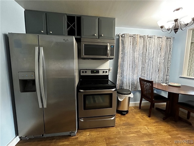 kitchen featuring stainless steel appliances, gray cabinets, a chandelier, and light hardwood / wood-style flooring