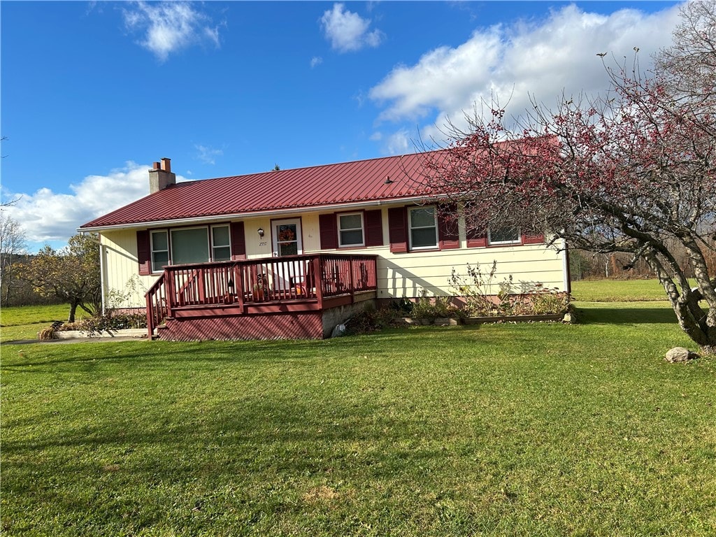 rear view of property featuring a wooden deck and a yard