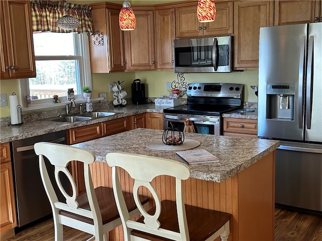 kitchen with a breakfast bar area, stainless steel appliances, sink, a center island, and dark hardwood / wood-style flooring