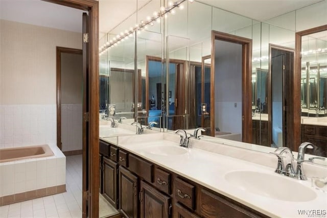 bathroom featuring vanity, a relaxing tiled tub, and tile patterned flooring