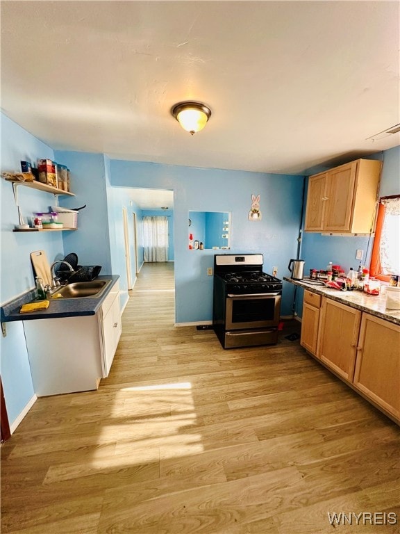 kitchen with sink, gas range oven, and light hardwood / wood-style floors