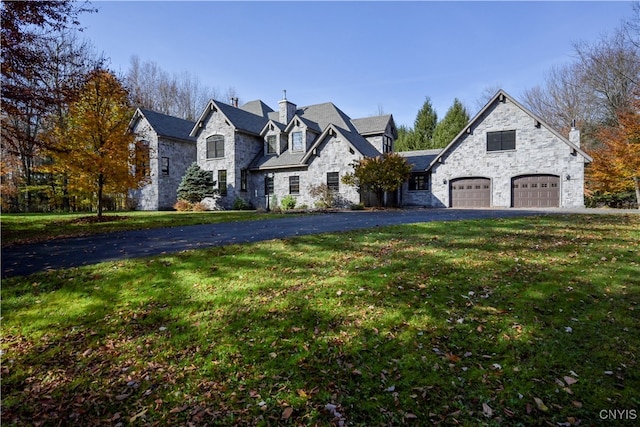 french provincial home with a front yard and a garage