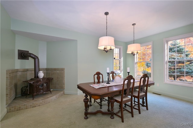 dining space with light carpet and a wood stove