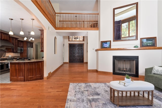 living room featuring a high ceiling, a notable chandelier, and light hardwood / wood-style floors