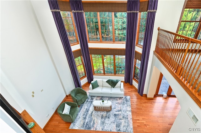 living room with a wealth of natural light, a high ceiling, and light hardwood / wood-style flooring