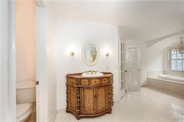 bathroom featuring toilet, tile patterned flooring, vanity, and tiled bath