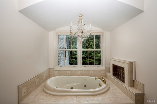 bathroom featuring lofted ceiling, a chandelier, and tiled tub