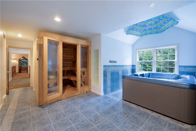 bathroom featuring a tub, tile patterned flooring, tile walls, and vaulted ceiling