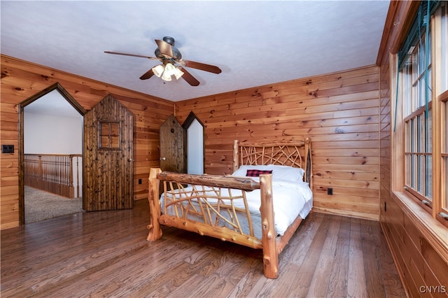 bedroom featuring hardwood / wood-style flooring, wooden walls, and ceiling fan