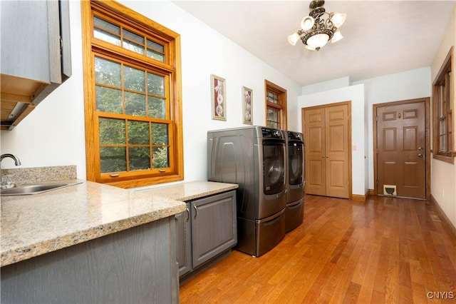 laundry area with cabinets, a chandelier, light hardwood / wood-style flooring, sink, and washer and clothes dryer