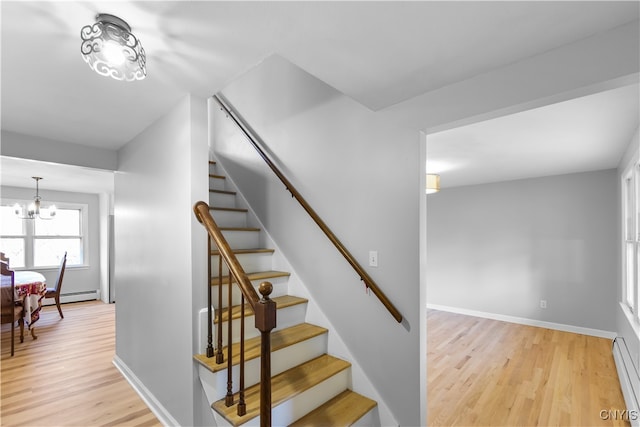 stairway featuring wood-type flooring, a baseboard radiator, and a chandelier