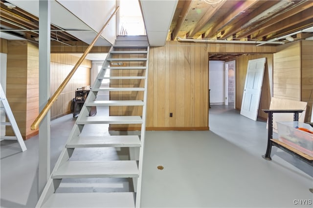 staircase featuring concrete flooring and wood walls