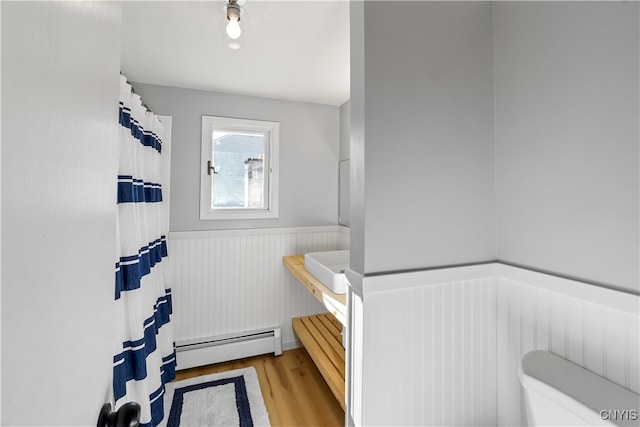 bathroom featuring baseboard heating, hardwood / wood-style floors, and toilet