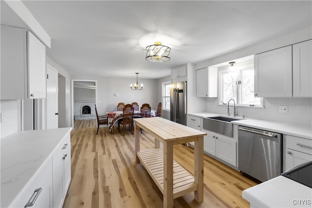 kitchen with white cabinets, light wood-type flooring, appliances with stainless steel finishes, and sink