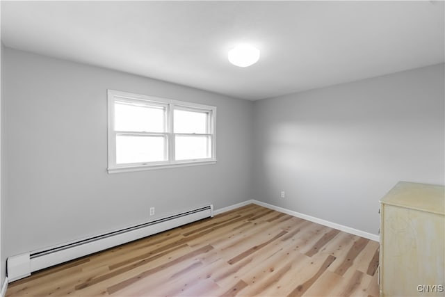 spare room featuring baseboard heating and light hardwood / wood-style flooring