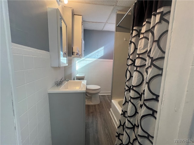 full bathroom with a drop ceiling, toilet, tile walls, vanity, and hardwood / wood-style flooring