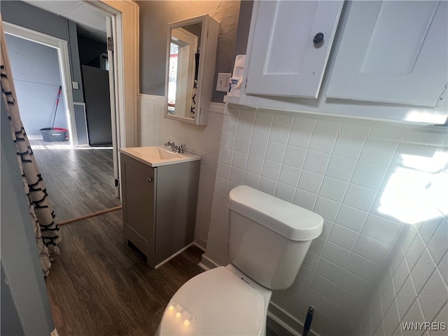 bathroom with vanity, toilet, hardwood / wood-style flooring, and tile walls