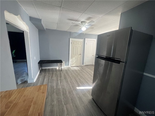 kitchen featuring stainless steel fridge, a drop ceiling, wood-type flooring, and ceiling fan