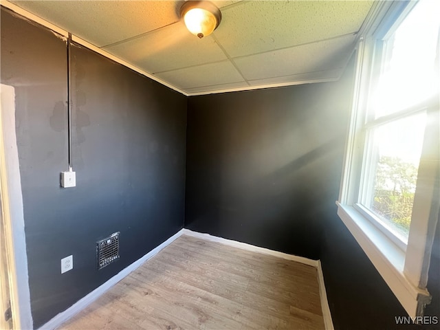 unfurnished room with a drop ceiling and hardwood / wood-style floors