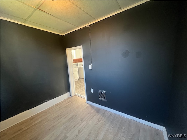 spare room featuring a paneled ceiling and light wood-type flooring