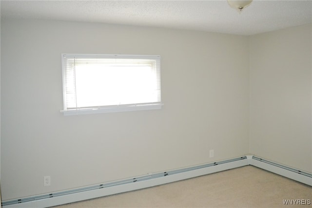 spare room with a textured ceiling, carpet floors, and a baseboard heating unit