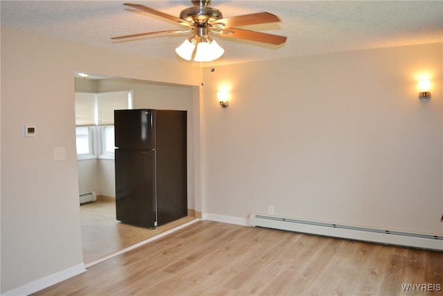 spare room with ceiling fan, light wood-type flooring, a textured ceiling, and a baseboard heating unit