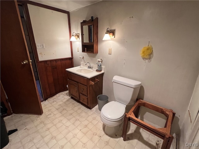 bathroom featuring vanity, toilet, and wooden walls