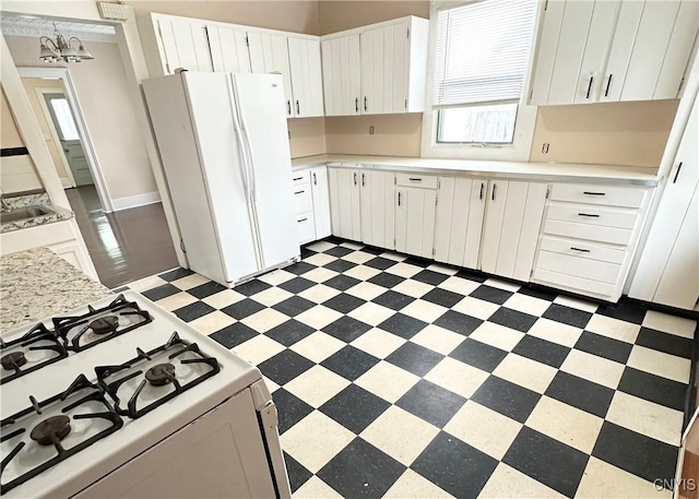 kitchen featuring white cabinetry, white appliances, decorative light fixtures, and sink