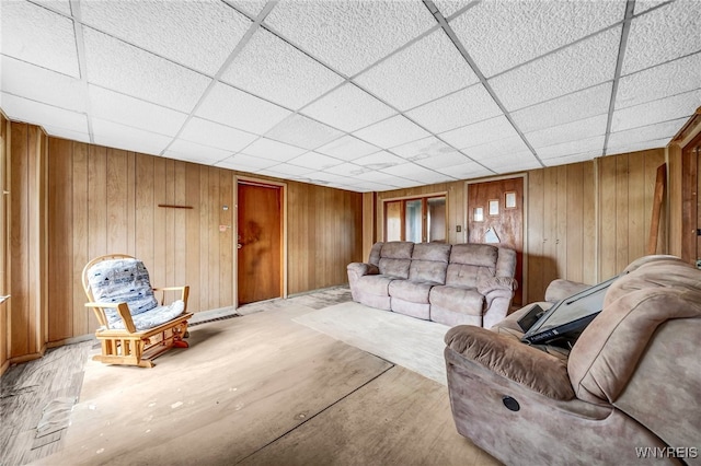 living room with a paneled ceiling and wood walls