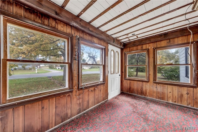 unfurnished sunroom featuring beamed ceiling and a wealth of natural light