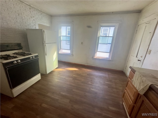 kitchen featuring dark hardwood / wood-style flooring, white appliances, a wealth of natural light, and brick wall