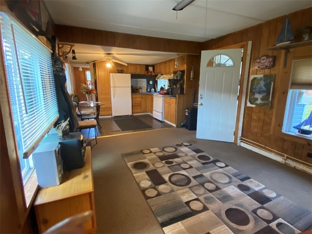 carpeted living room featuring wooden walls and ceiling fan