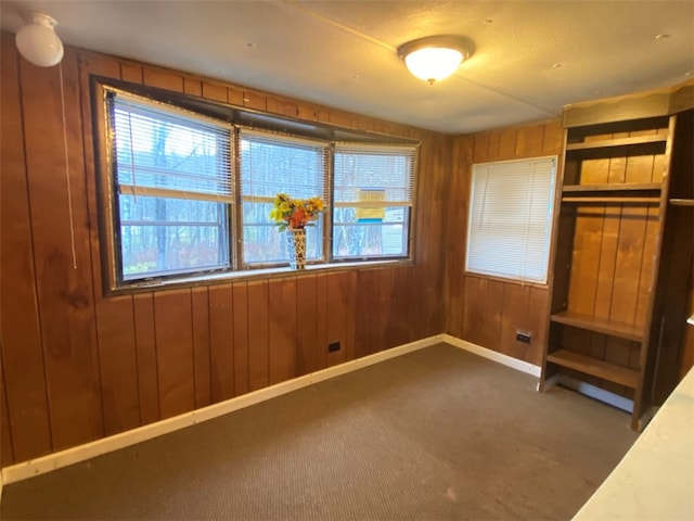 unfurnished bedroom with wood walls and dark colored carpet