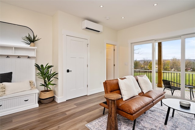 living area with a wall mounted air conditioner and hardwood / wood-style floors