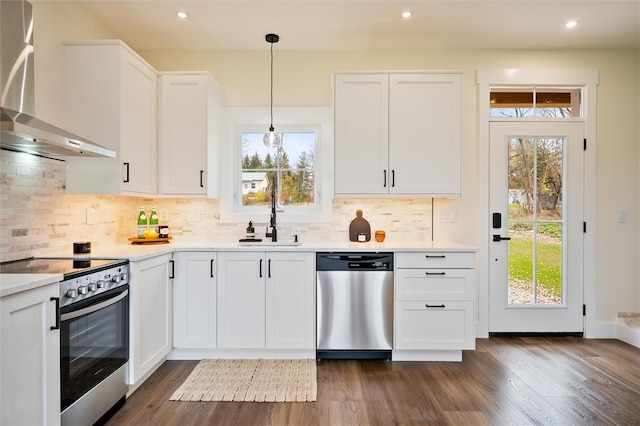 kitchen with dark hardwood / wood-style flooring, wall chimney exhaust hood, stainless steel appliances, pendant lighting, and white cabinets