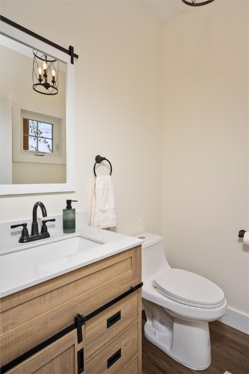 bathroom featuring wood-type flooring, vanity, a chandelier, and toilet