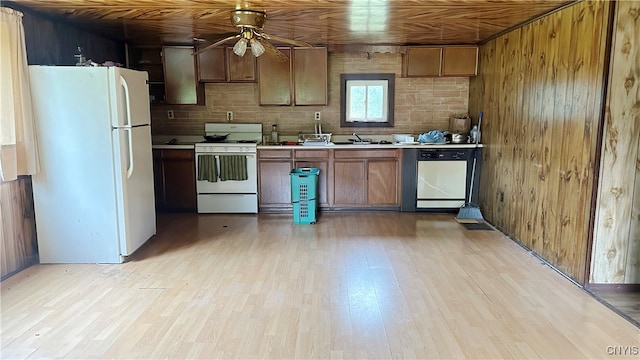 kitchen featuring light hardwood / wood-style floors, wood walls, sink, and white appliances