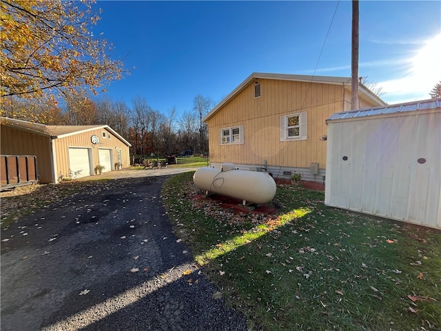 view of side of property featuring a garage, a lawn, and an outdoor structure