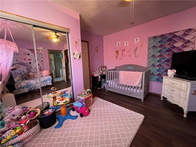 bedroom with dark hardwood / wood-style floors, a closet, and a nursery area