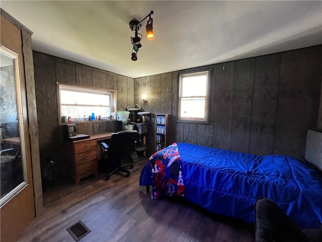 bedroom featuring dark hardwood / wood-style flooring, wood walls, multiple windows, and lofted ceiling