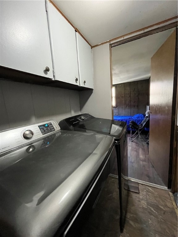 washroom featuring wooden walls, cabinets, and washing machine and clothes dryer