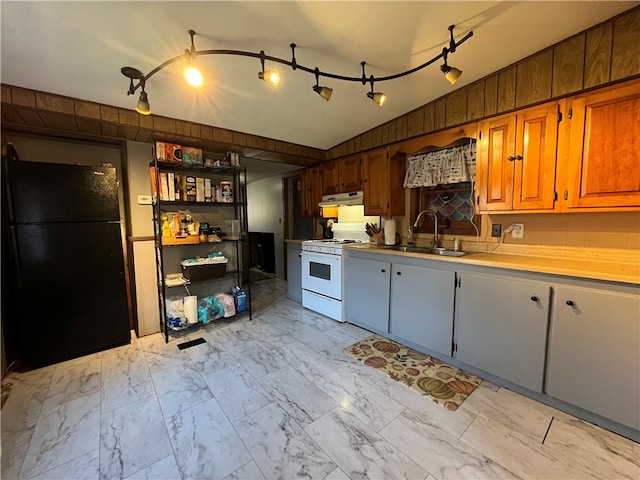 kitchen with sink, black fridge, vaulted ceiling, and white gas range