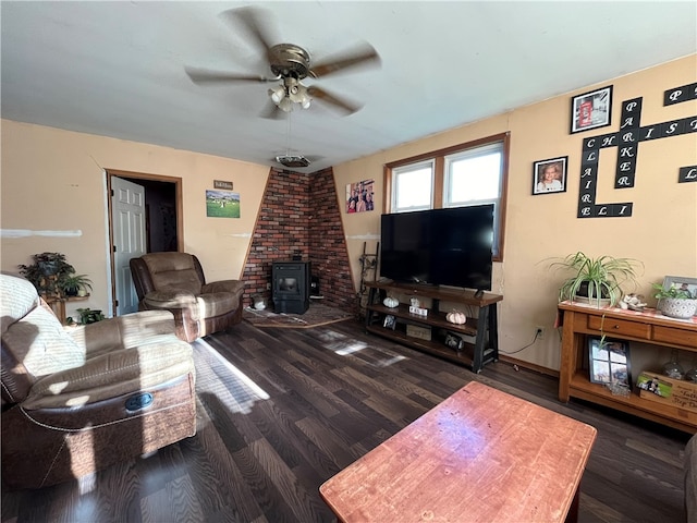 living room with dark wood-type flooring, a wood stove, and ceiling fan