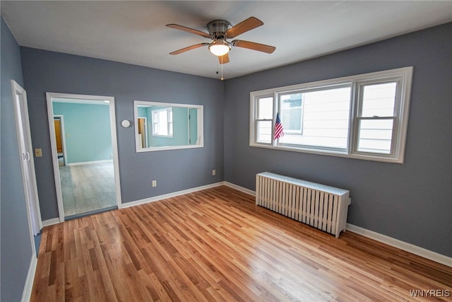 unfurnished bedroom with light wood-type flooring, ceiling fan, and radiator