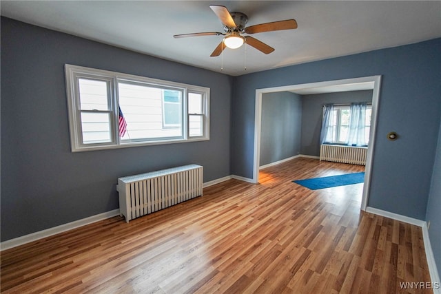 spare room with radiator heating unit, ceiling fan, and light hardwood / wood-style flooring